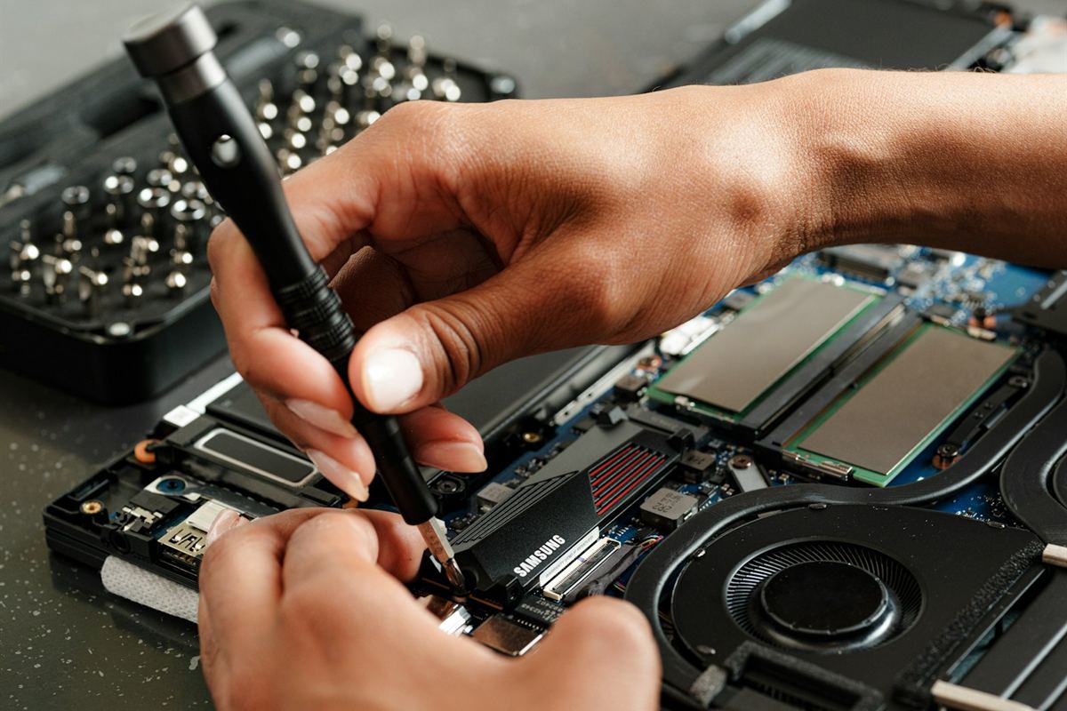 A replacement SSD being fitted into a laptop, with a bit set open alongside.